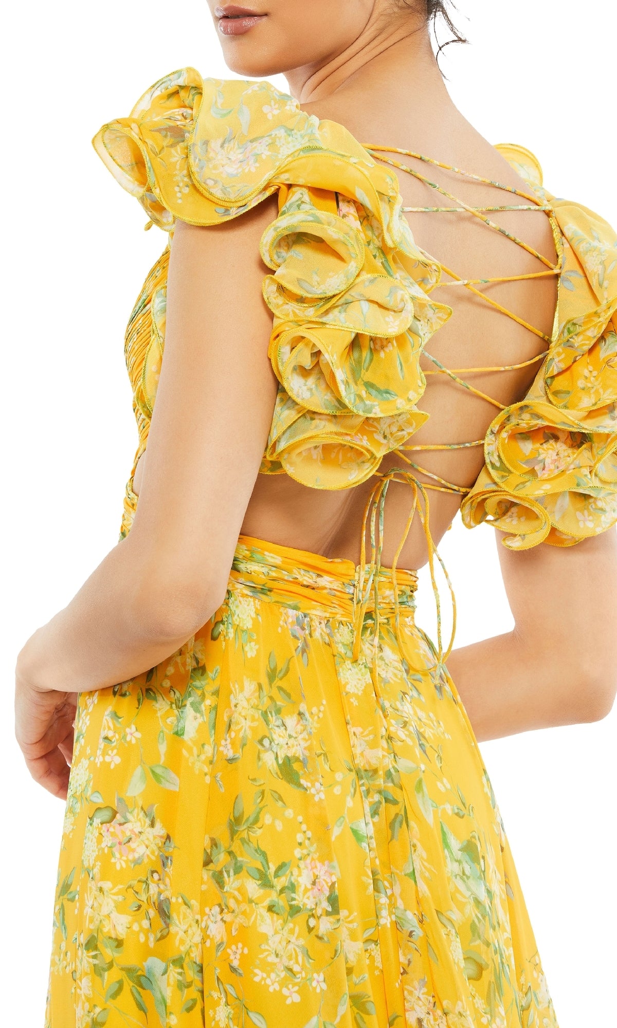 A woman wears the Mac Duggal 67803 Ruffled Long Print Formal Dress featuring a yellow floral print, ruffled sleeves, and an open back with crisscross lace-up detailing.